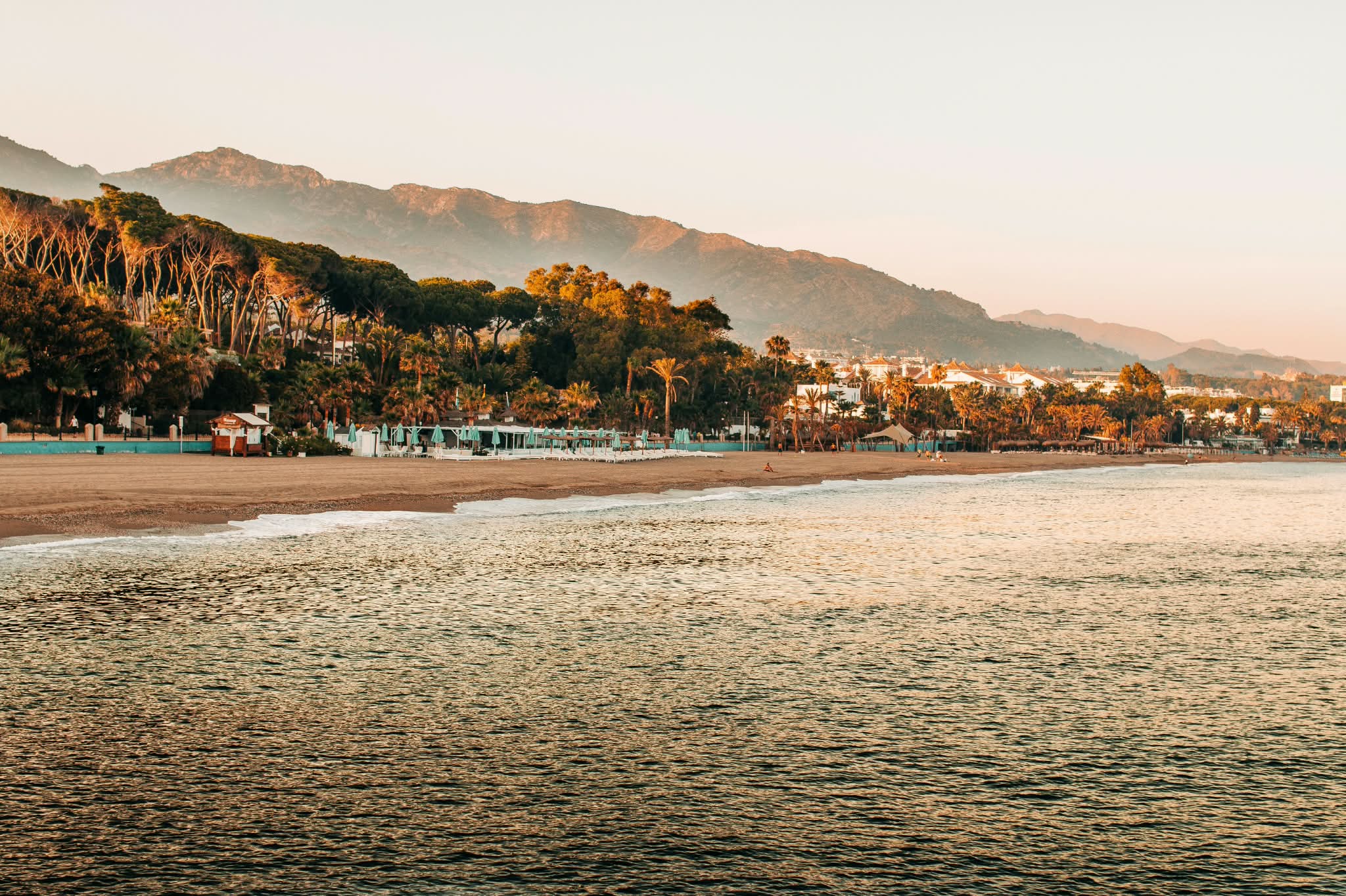 Plage de la Costa del Sol au coucher du soleil, entre pinèdes et montagnes.